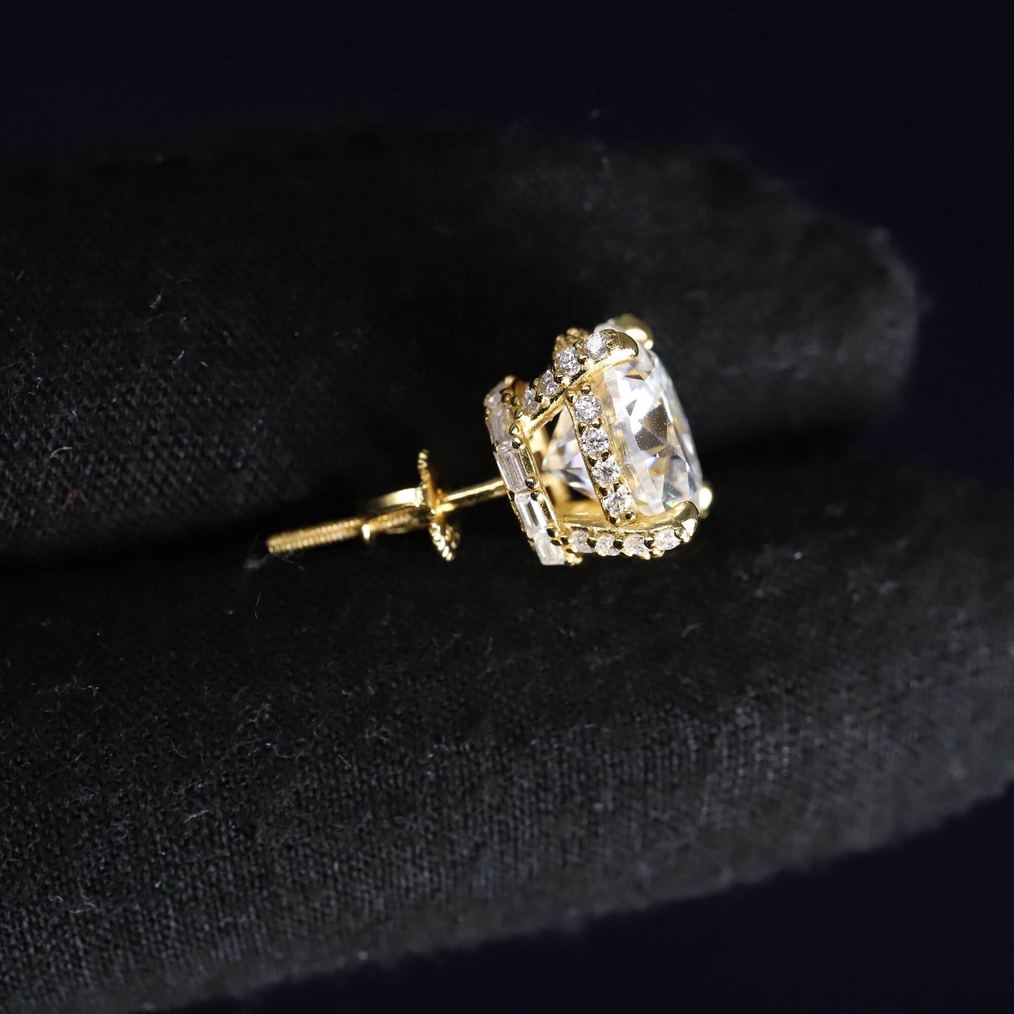 Gold earring with a clear gemstone on a black background