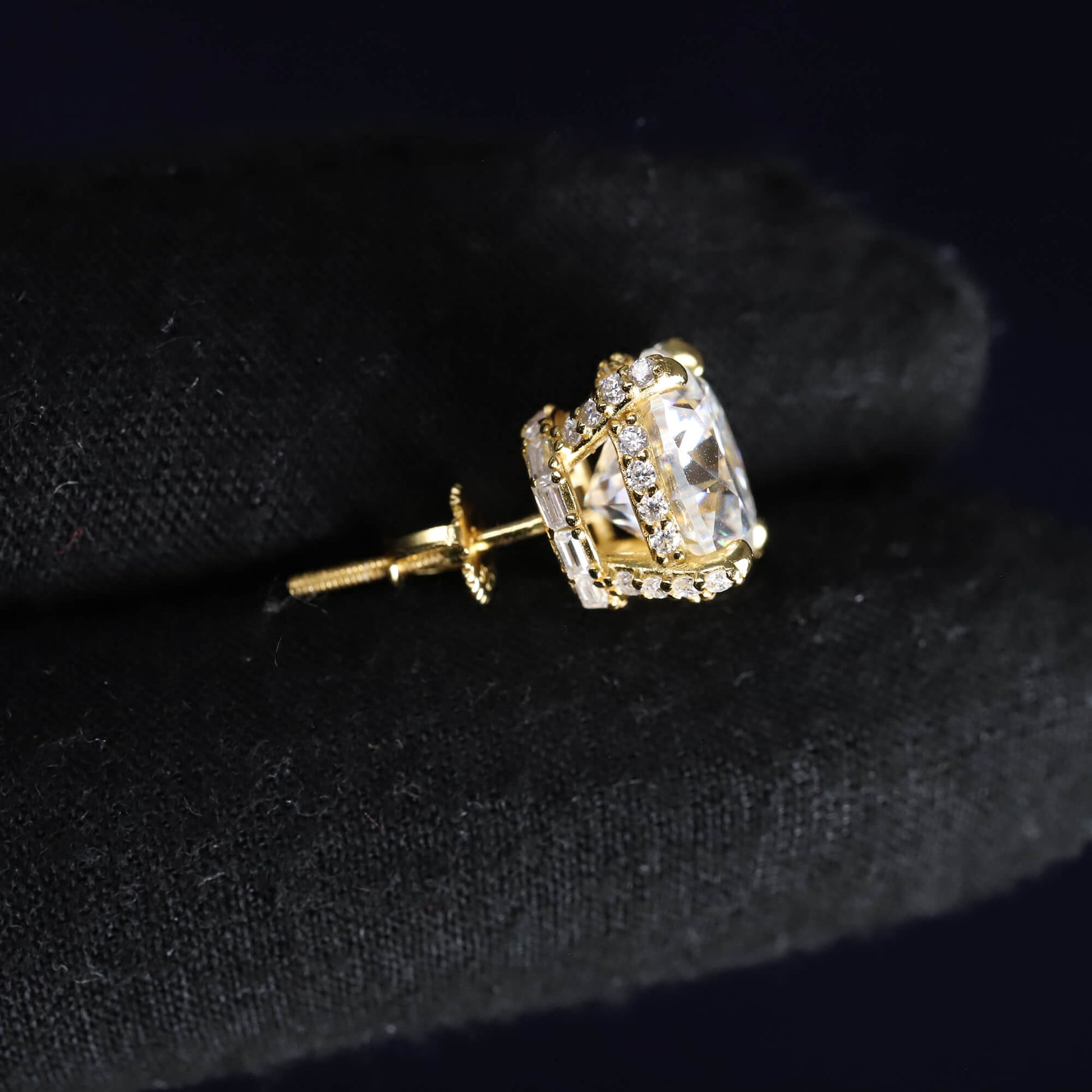 Gold earring with a clear gemstone on a black background