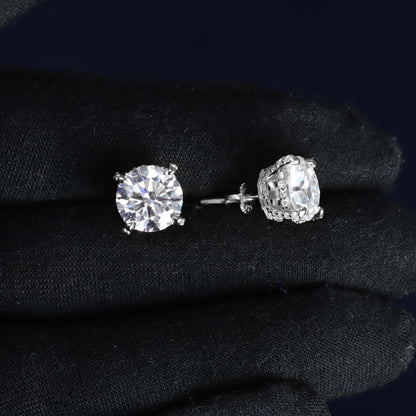Pair of diamond stud earrings on a dark fabric background