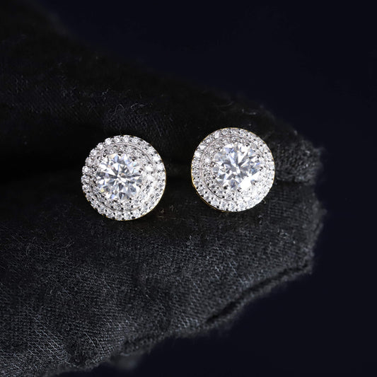 Pair of silver stud earrings with clear gemstones on a black textured fabric background