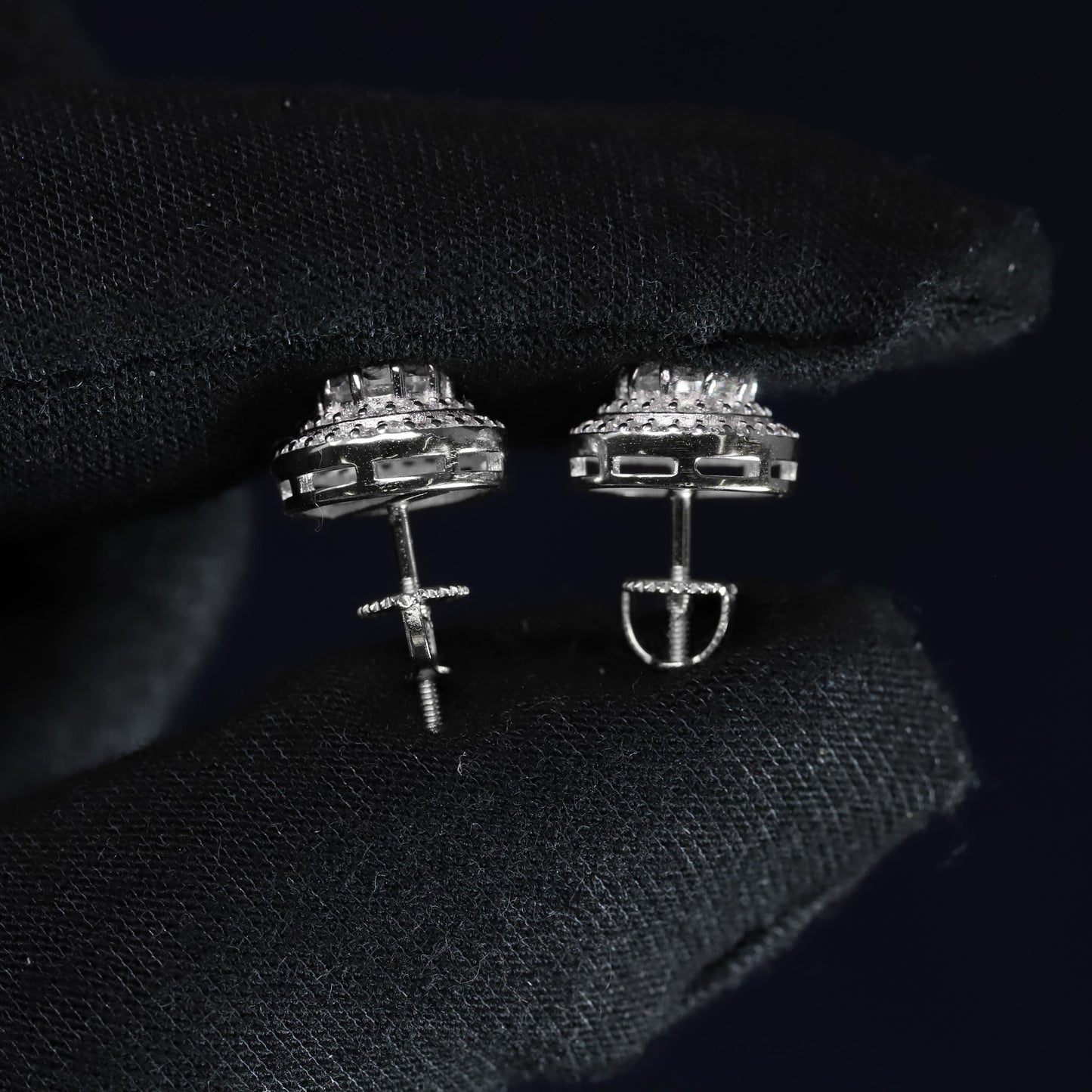 Pair of silver earrings on a black textured surface