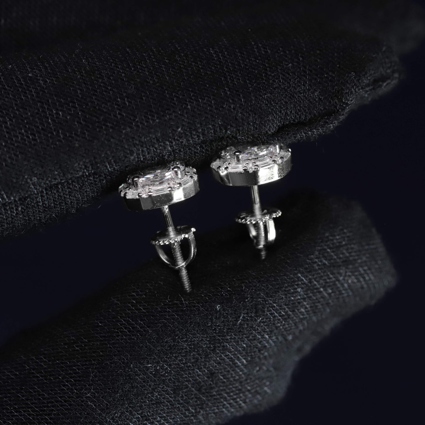 Pair of silver stud earrings on a black fabric background