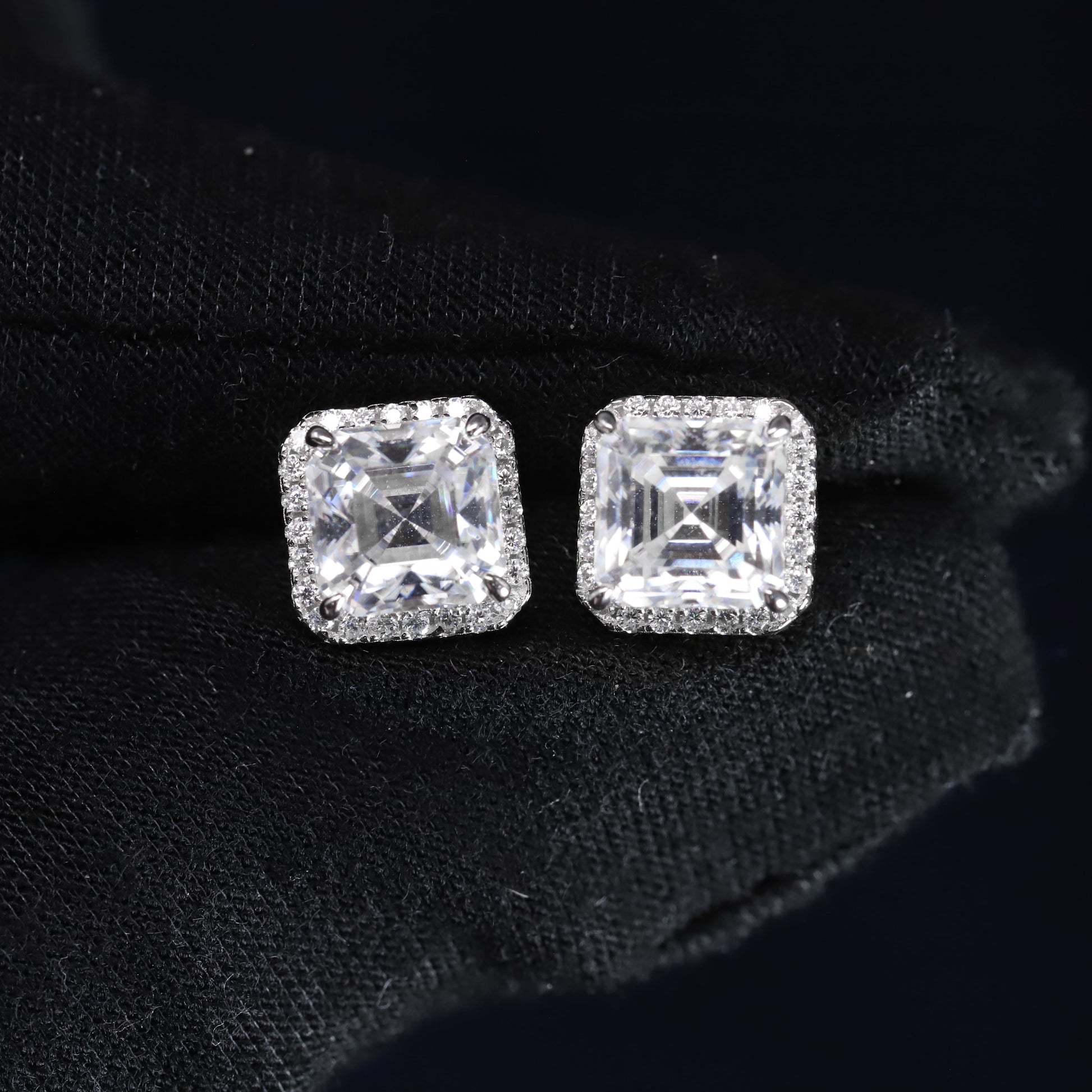 Pair of square-cut diamond earrings on a black background