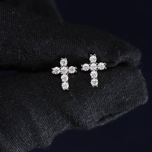 Pair of diamond cross earrings on a black fabric background