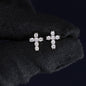 Pair of diamond cross earrings on a black fabric background