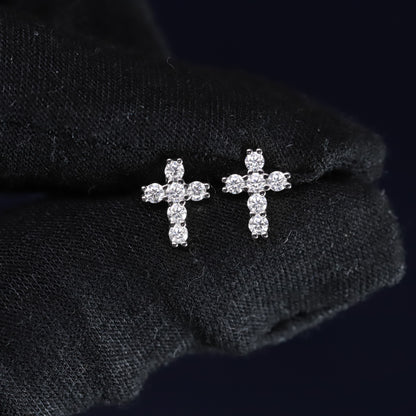 Pair of diamond cross earrings on a black fabric background