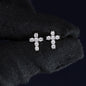 Pair of diamond cross earrings on a black fabric background