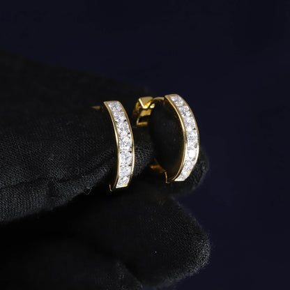 Gold hoop earrings with clear stones on a black surface