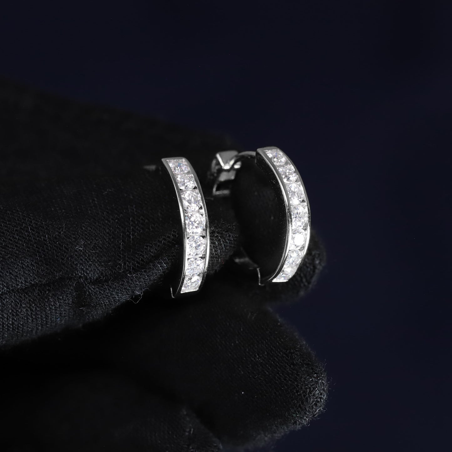 Silver hoop earrings with clear stones on a black background
