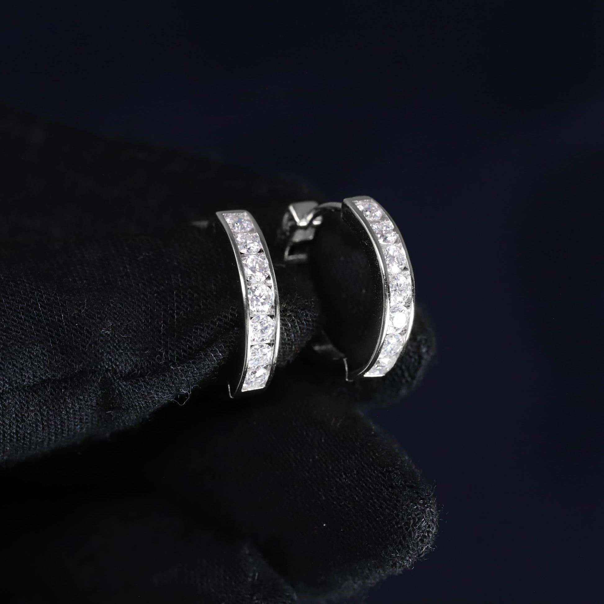 Silver hoop earrings with clear stones on a black background