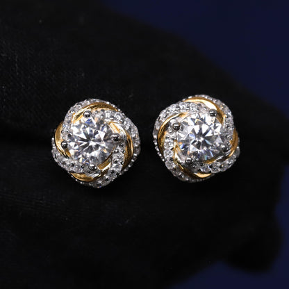 Pair of gold and silver earrings with clear gemstones on a dark background