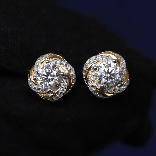 Pair of gold and silver earrings with clear gemstones on a dark background