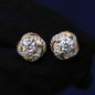 Pair of gold and silver earrings with clear gemstones on a dark background