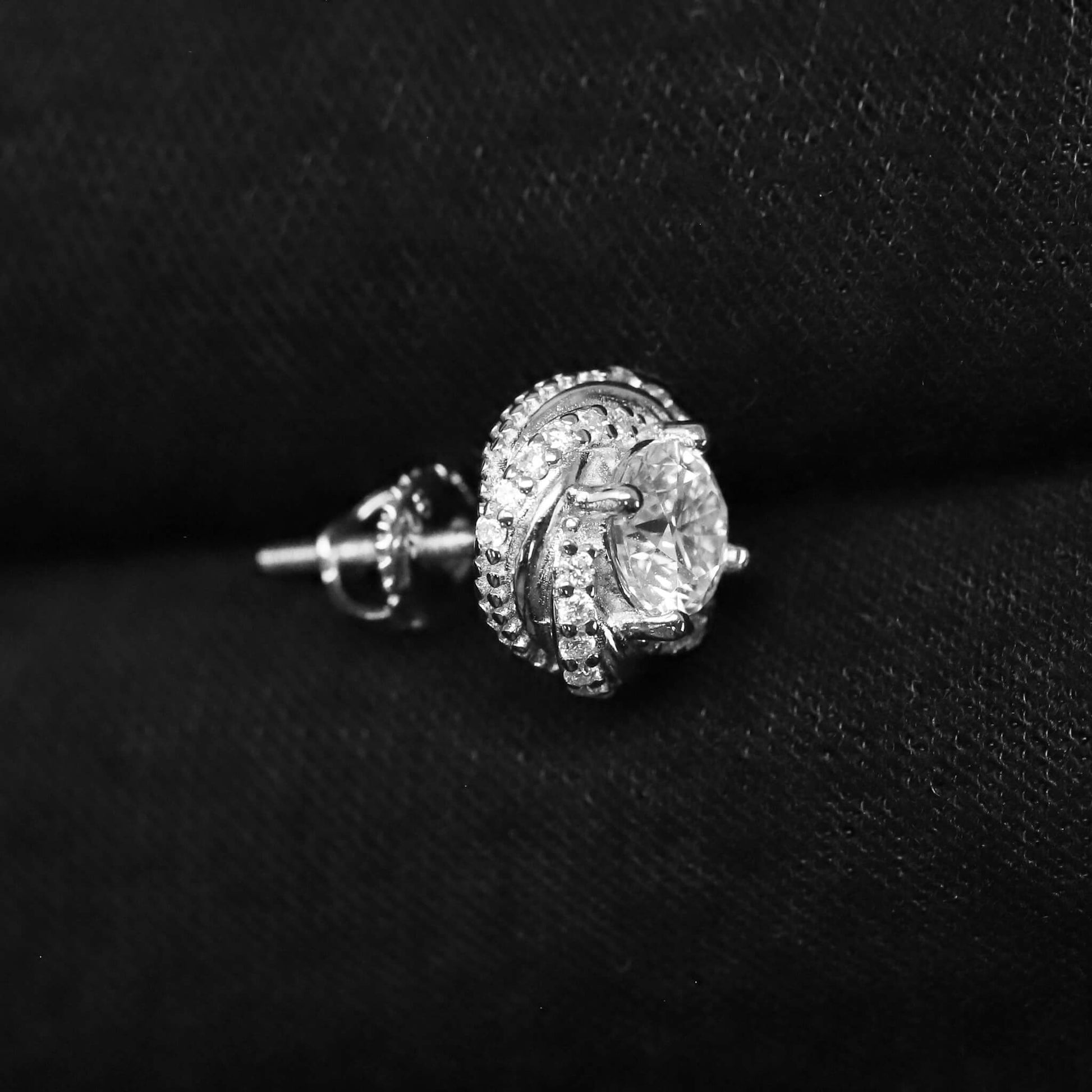 Silver earring with a large central gemstone on a black background