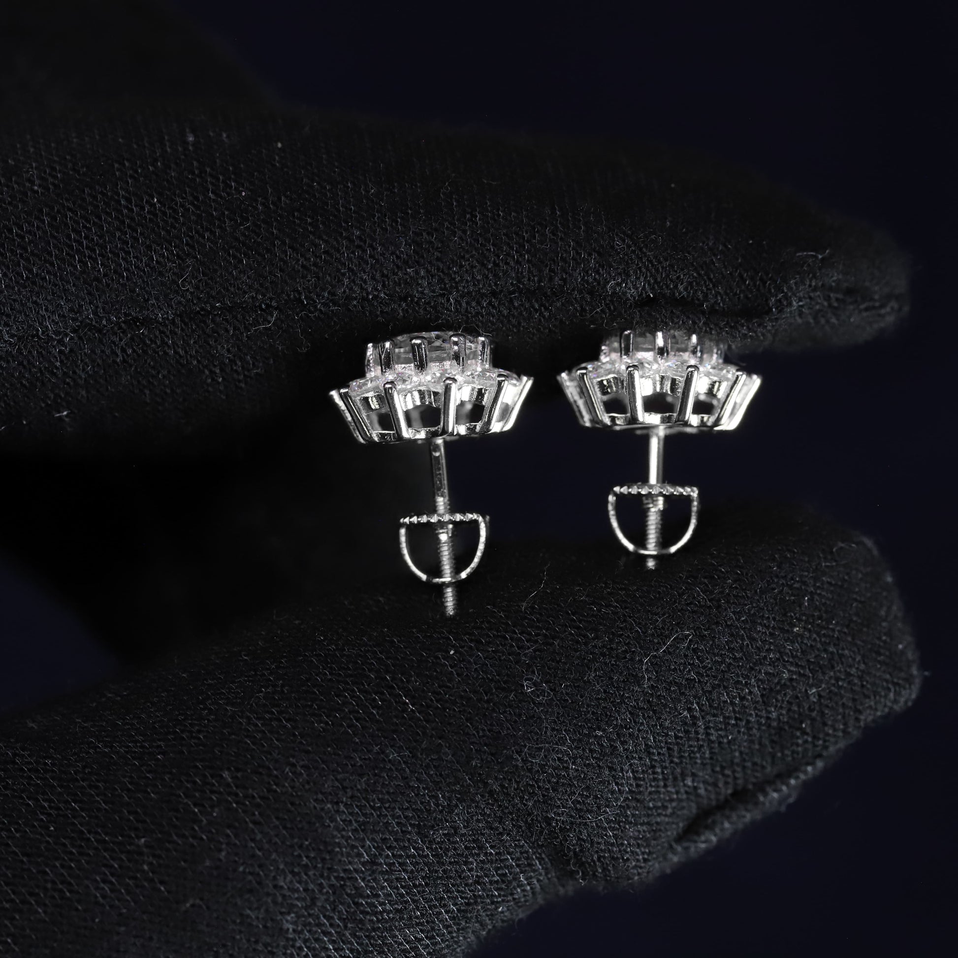 Pair of silver earrings with clear gemstones on a black background