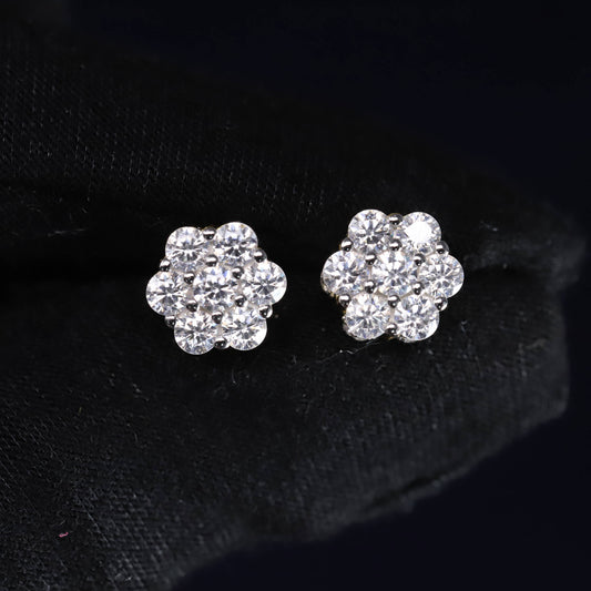 Pair of silver flower-shaped earrings with clear stones on a black background