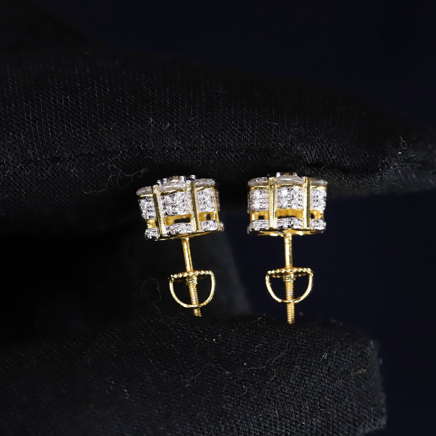 Gold earrings with clear gemstones on a black background
