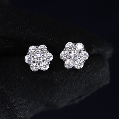 Pair of silver flower-shaped earrings with clear stones on a black background