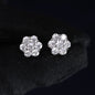 Pair of silver flower-shaped earrings with clear stones on a black background