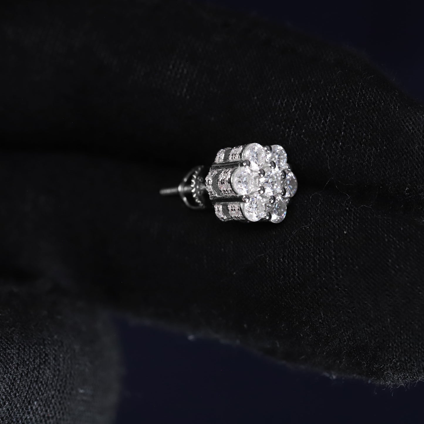 Silver floral earring on a black velvet background