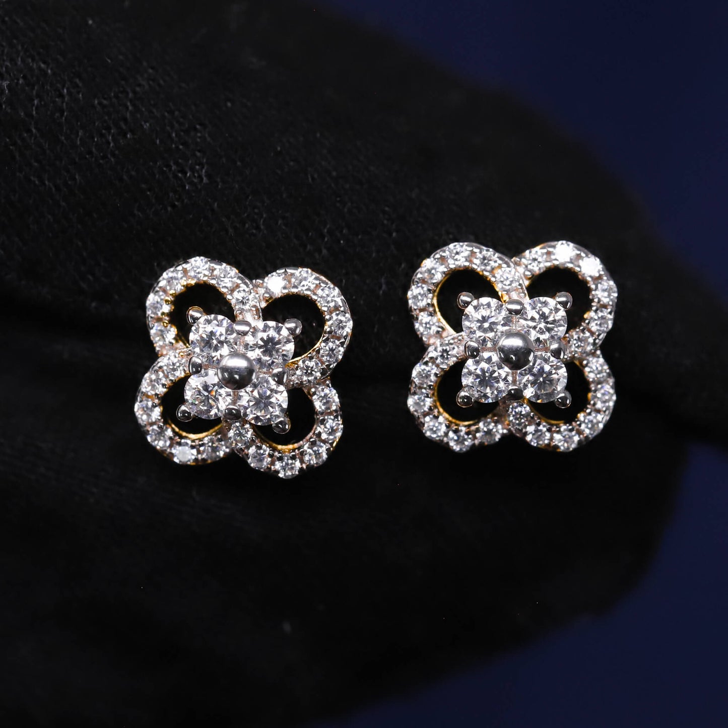 Butterfly-shaped earrings with clear gemstones on a dark background