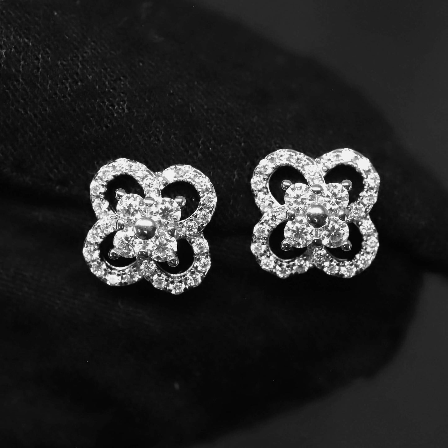 Pair of silver butterfly-shaped earrings with clear gemstones on a black background