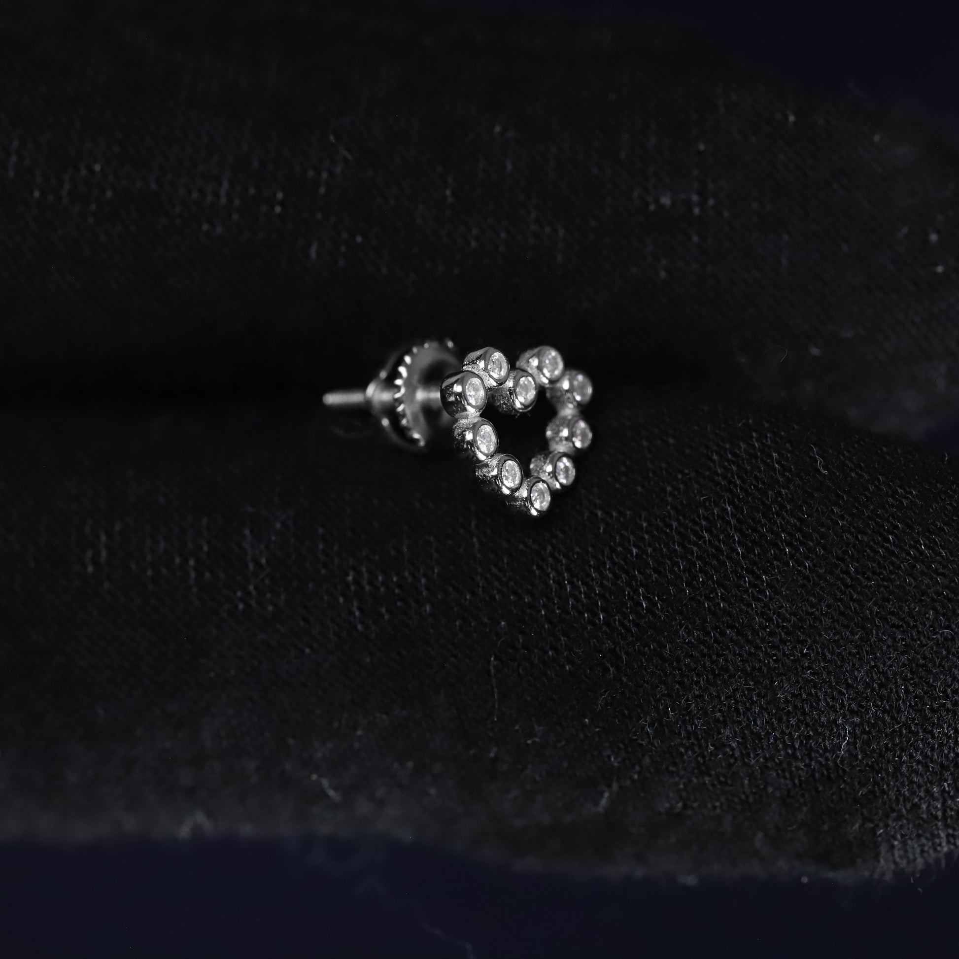 Heart-shaped earring with clear stones on a black velvet background