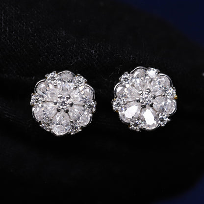 Pair of silver floral earrings with clear gemstones on a dark background