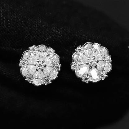 Pair of silver floral earrings with clear gemstones on a black background