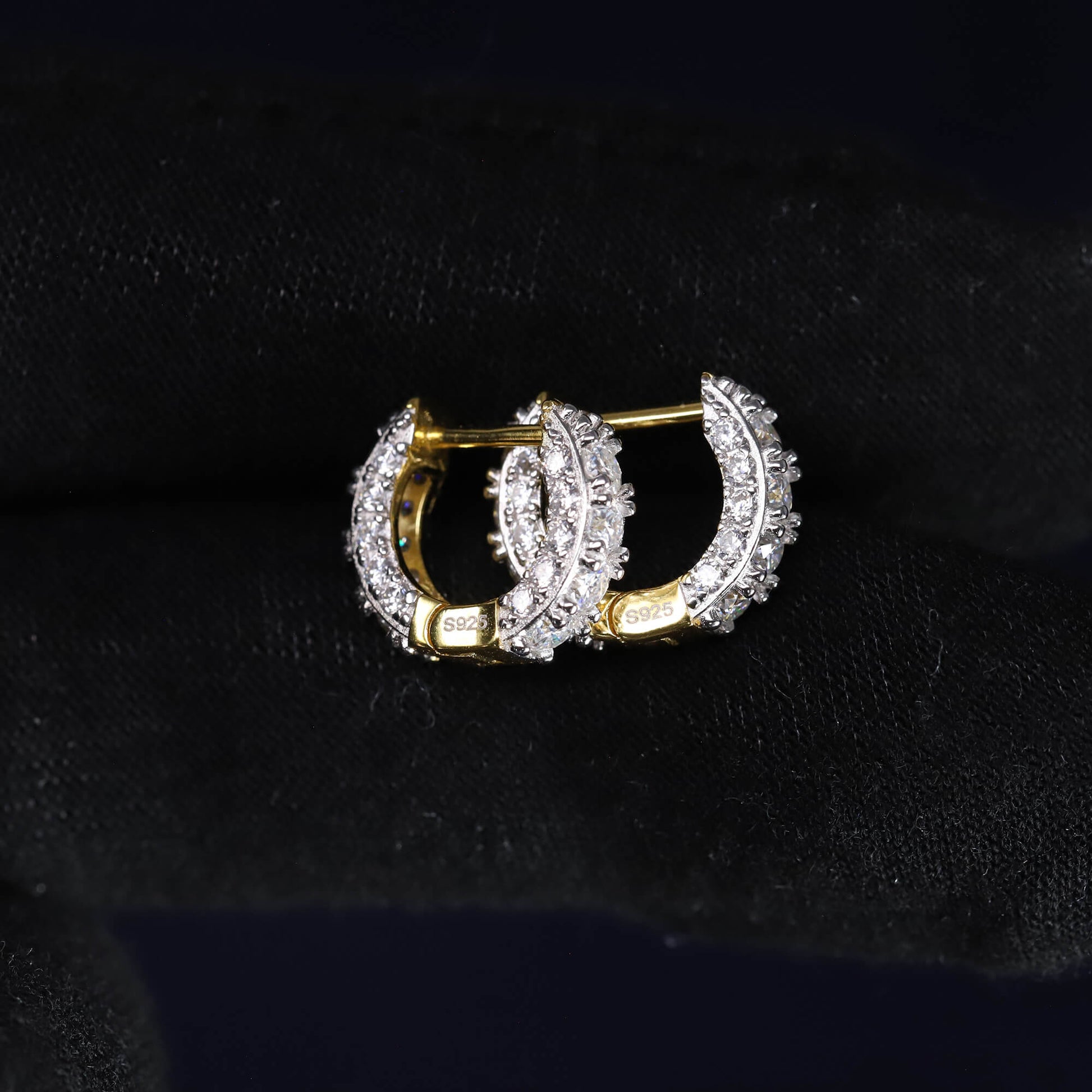 Pair of gold and diamond hoop earrings on a black background