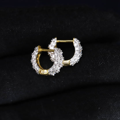 Pair of gold hoop earrings with clear gemstones on a black background