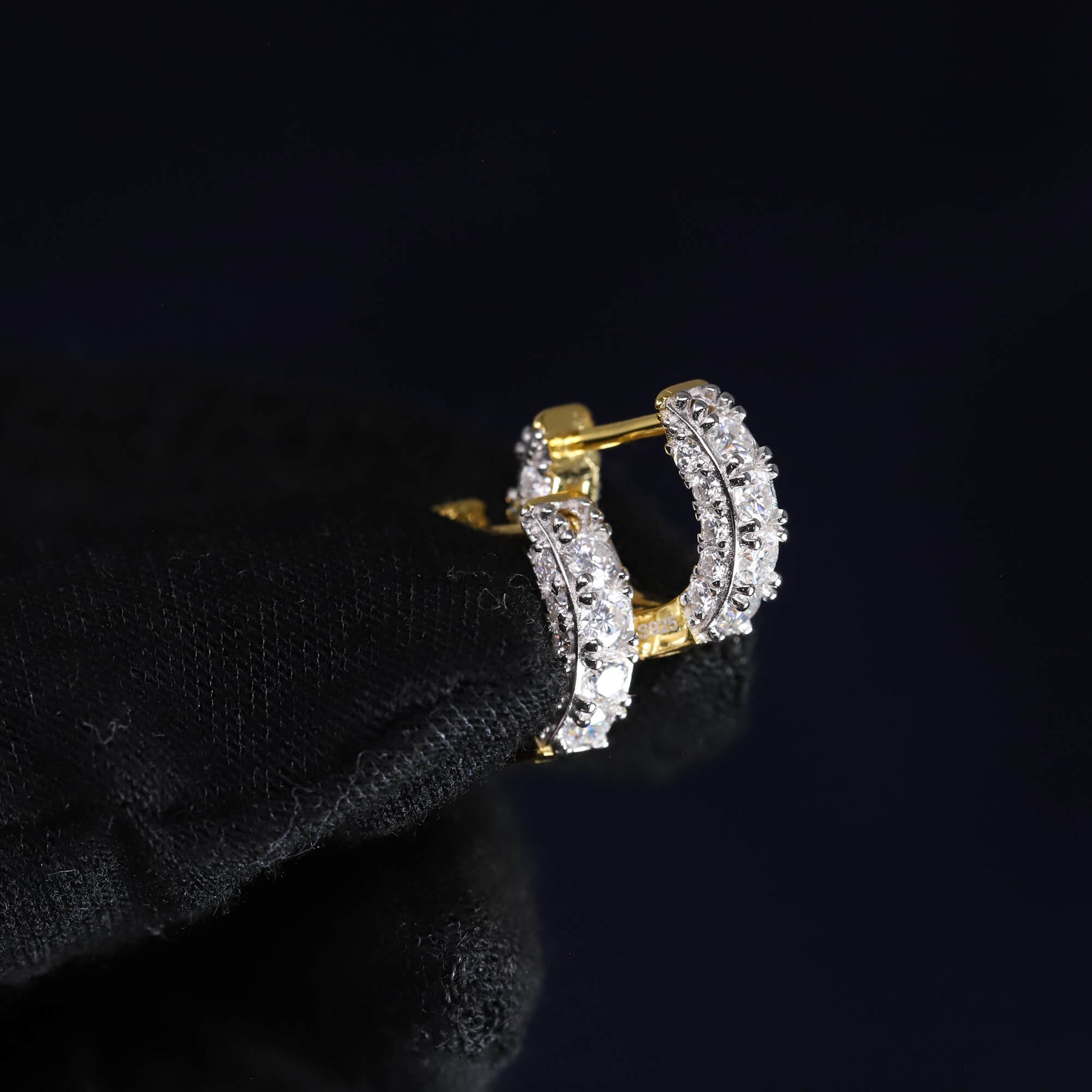 Gold and diamond hoop earring on a black background