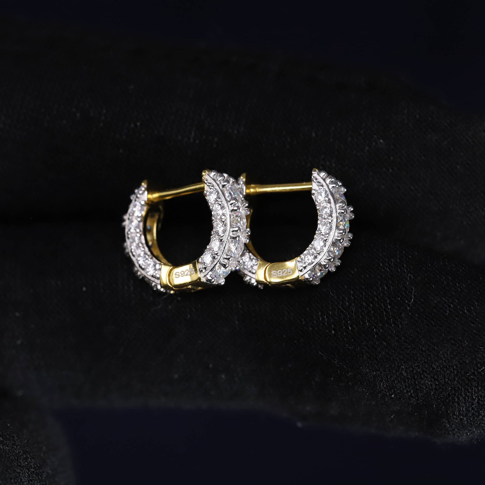 Gold hoop earrings with diamond accents on a black background