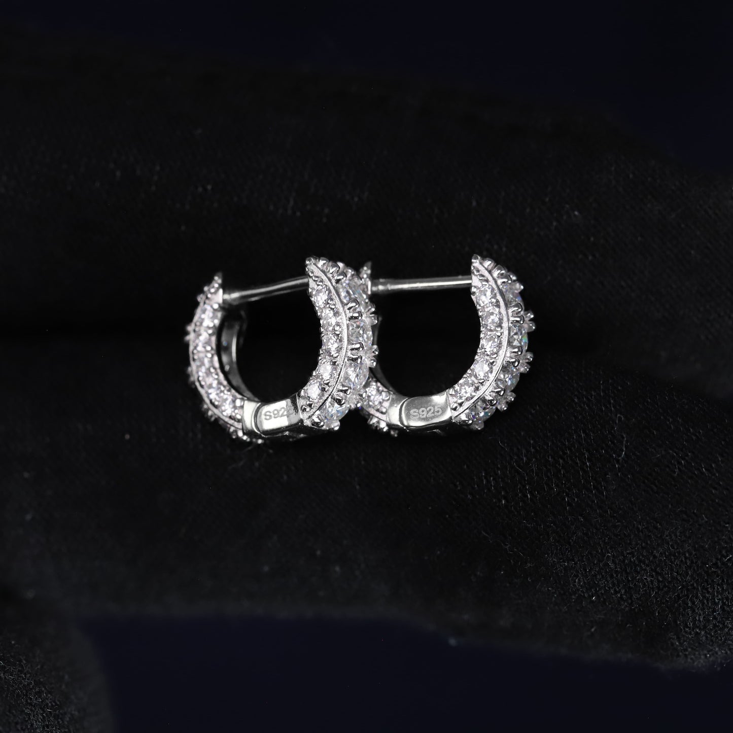 Gold hoop earrings with diamond accents on a black background