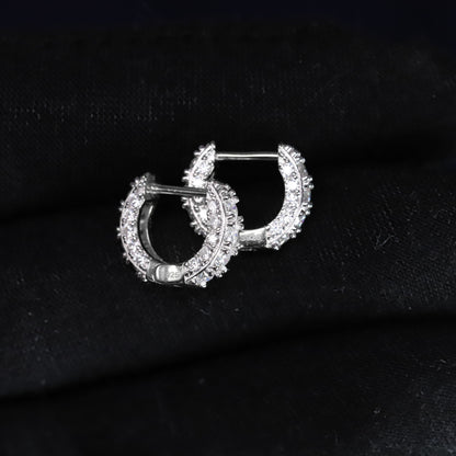 Pair of silver hoop earrings with clear stones on a black fabric background