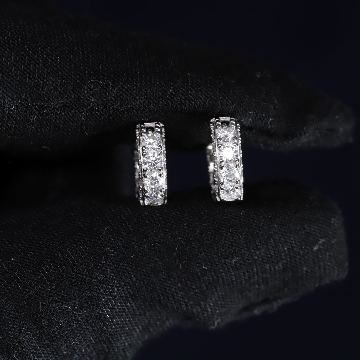 Pair of silver hoop earrings on a black fabric background