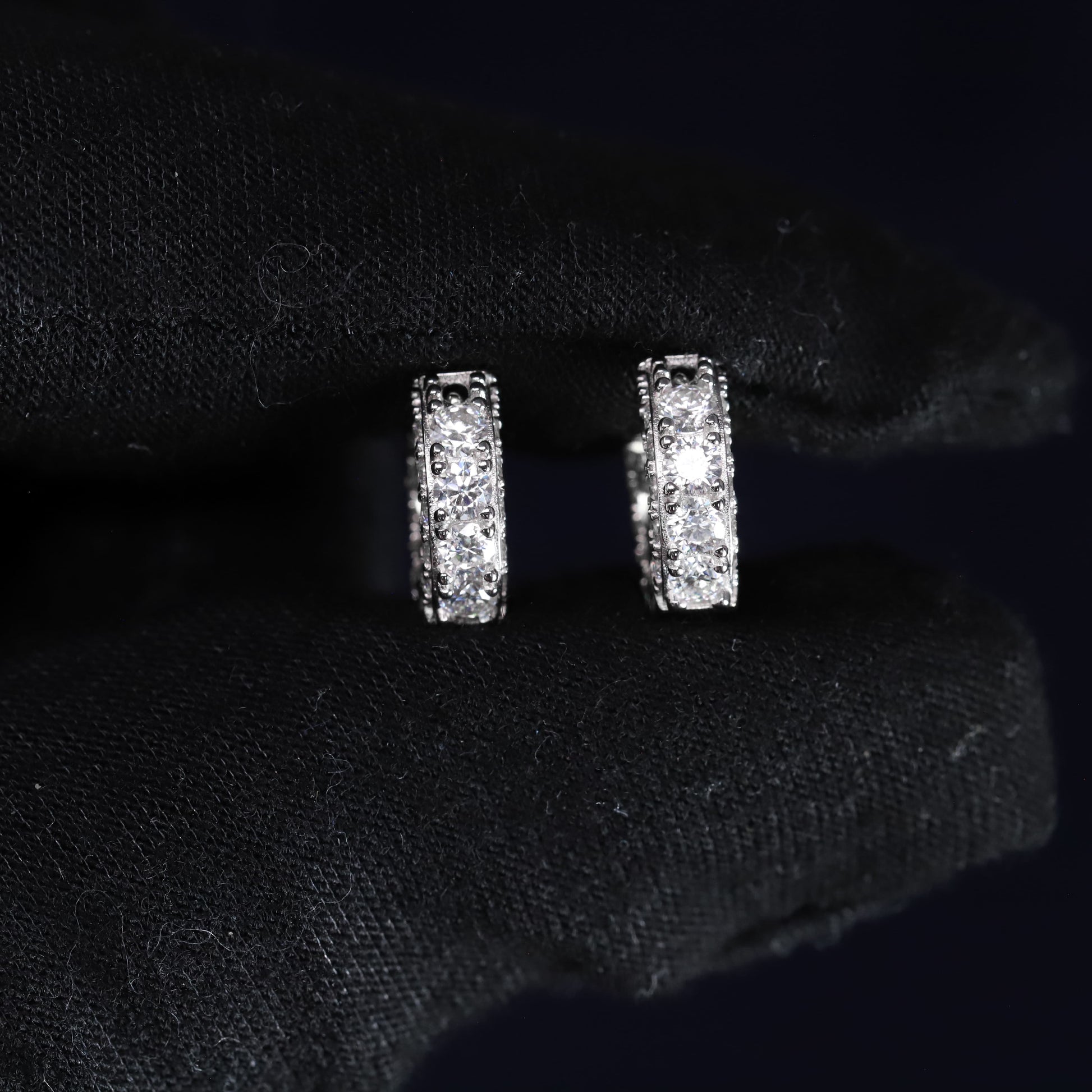 Pair of silver hoop earrings on a black fabric background