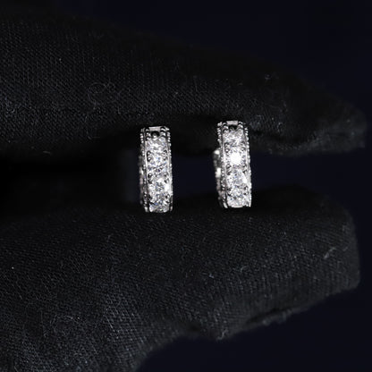 Pair of silver hoop earrings on a black fabric background