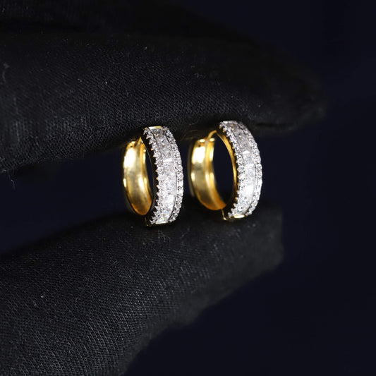 Gold hoop earrings with embedded stones on a black background