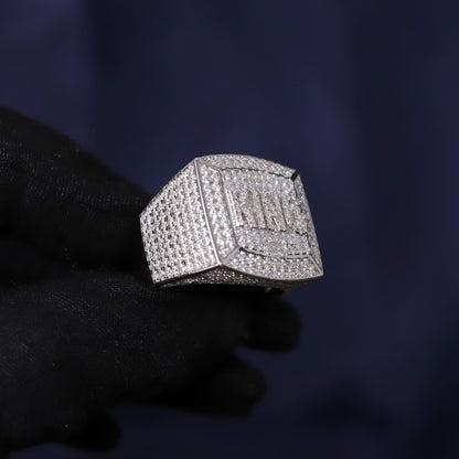 Silver ring with gemstones held by a gloved hand against a dark background